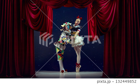 Expression in motion. Mime and ballerina posing dramatically on stage under red curtains. 132449852