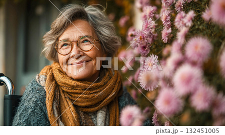 An elderly woman with a kind expression, smiling as she sits in a wheelchair outside.	 132451005