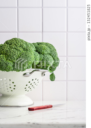 Raw broccoli in a white enamel colander 132451825