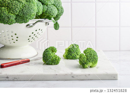Raw broccoli in a white enamel colander Raw broccoli in a white enamel colander 132451828