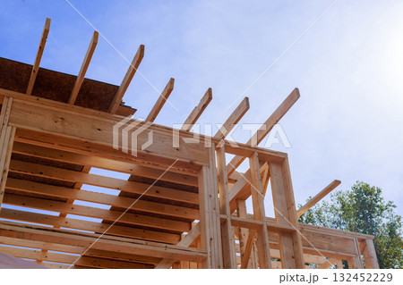 Wooden beams rafters are being installed on house frame new construction work. 132452229