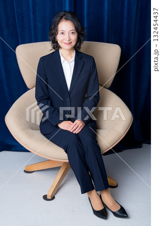 大きな椅子に座るミドルビジネスウーマン 132454437