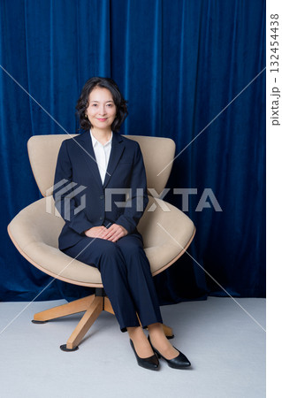 大きな椅子に座るミドルビジネスウーマン 132454438