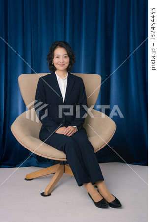 大きな椅子に座るミドルビジネスウーマン 132454455