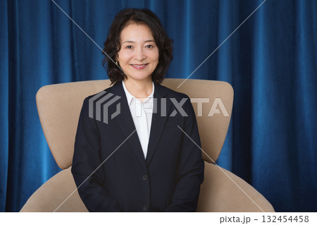 大きな椅子に座るミドルビジネスウーマン 132454458