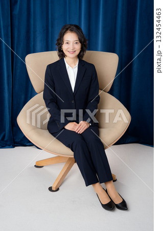 大きな椅子に座るミドルビジネスウーマン 132454463