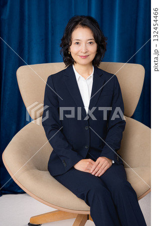 大きな椅子に座るミドルビジネスウーマン 132454466
