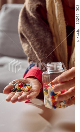 Senior woman pouring colorful pills from plastic jar into her palm Senior woman pouring colorful pills from plastic jar into her palm 132454502