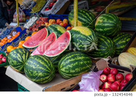 Watermelons and fresh fruits in outdoor market stall and juicy red watermelons cut in half. 132454846