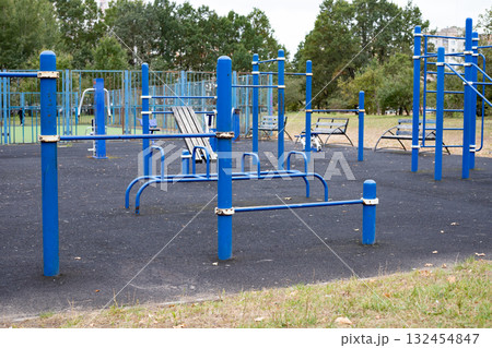 Urban sports ground with exercise equipment near residential buildings. A close-up of various exercise equipment on a playground Urban sports ground with exercise equipment near residential buildings. A close-up of various exercise equipment on a playground 132454847