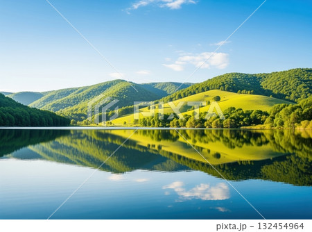 Serene nature landscape with lake reflecting green hills and blue sky Serene nature landscape with lake reflecting green hills and blue sky 132454964