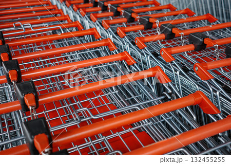 Row of shopping carts with red handles. The carts are lined up in a row and are all the same color Row of shopping carts with red handles. The carts are lined up in a row and are all the same color 132455255