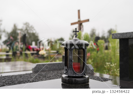 Somber cemetery scene with lantern and cross on a cloudy day Somber cemetery scene with lantern and cross on a cloudy day 132456422