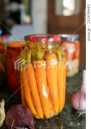 Pickled carrots in jar with fresh vegetables on kitchen counter. National Pickle Day Pickled carrots in jar with fresh vegetables on kitchen counter. National Pickle Day 132456443