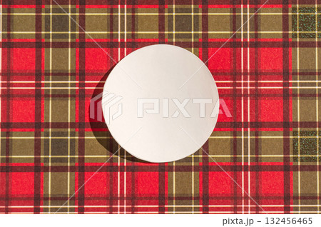 Round white placemat on red and brown plaid pattern background Round white placemat on red and brown plaid pattern background 132456465