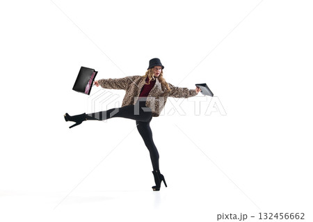 Stylish woman in leopard print jacket posing with shopping bags in dynamic expressive motion Stylish woman in leopard print jacket posing with shopping bags in dynamic expressive motion 132456662