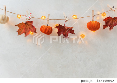 Autumn Garland with Leaves, Pumpkins, Berries, and Lights on Textured Wall Autumn Garland with Leaves, Pumpkins, Berries, and Lights on Textured Wall 132456692