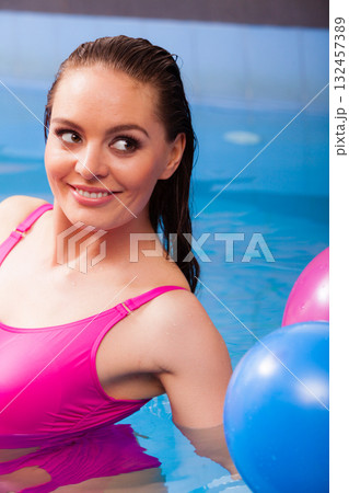 Woman having fun with balloons in water pool Woman having fun with balloons in water pool 132457389
