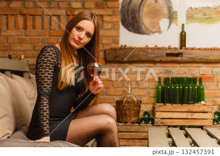 Woman tasting wine in rural cottage interior 132457391