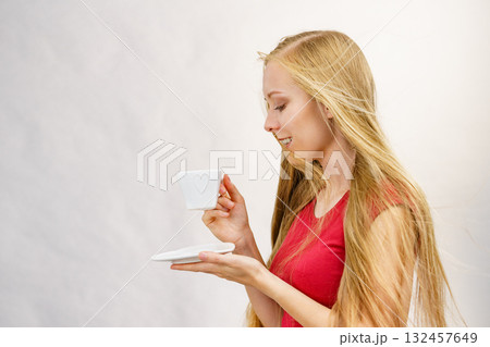 Blonde girl blowing hair holds coffee cup 132457649