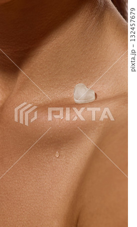 Close-up collarbone with melting ice heart and water drop on skin surface. 132457679
