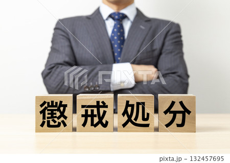 「懲戒処分」と書かれたブロックと腕組みをするビジネスマン 132457695