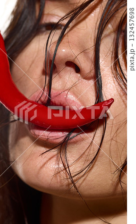 Female lips touching red chili pepper symbolizing intensity and desire Female lips touching red chili pepper symbolizing intensity and desire 132457698