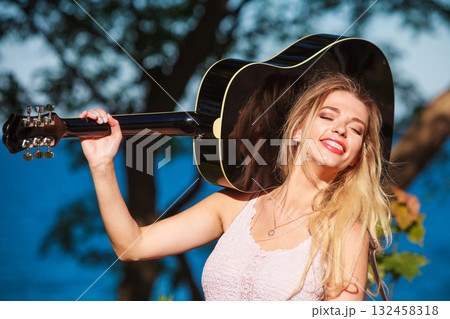 Blonde woman with acoustic guitar on seaside 132458318