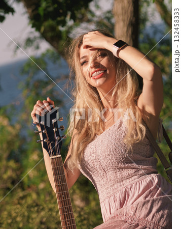 Woman playing acoustic guitar in park Woman playing acoustic guitar in park 132458333