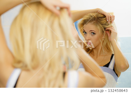 Woman fixing her hair in mirror 132458643