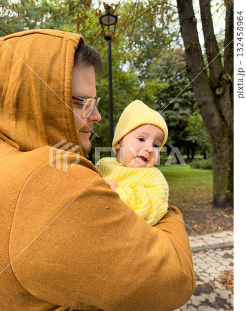 Man Holding Baby in Yellow Outfit Outdoors 132458964