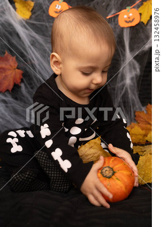Baby in Skeleton Costume with Pumpkin and Leaves 132458976