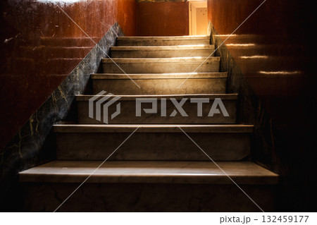 Vintage marble staircase inside an old Roman house with warm sunlight casting dramatic shadows on polished walls Vintage marble staircase inside an old Roman house with warm sunlight casting dramatic shadows on polished walls 132459177