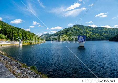 Panoramic view of the Sance reservoir and lake in summer, surrounded by green forests and blue sky, located near the Beskydy mountains in the Czech Republic. 132459784