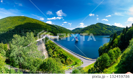 Panoramic view of the Sance reservoir and lake in summer, surrounded by green forests and blue sky, located near the Beskydy mountains in the Czech Republic. Panoramic view of the Sance reservoir and lake in summer, surrounded by green forests and blue sky, located near the Beskydy mountains in the Czech Republic. 132459786