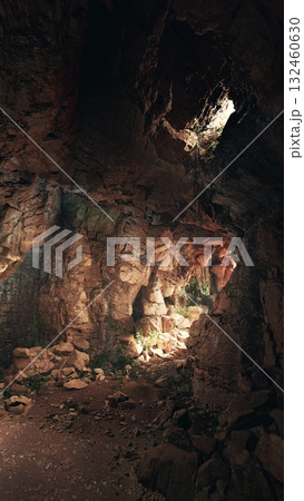 A cave filled with rocks and water, illuminated by rays of sunlight penetrating through the stone walls. A cave filled with rocks and water, illuminated by rays of sunlight penetrating through the stone walls. 132460630