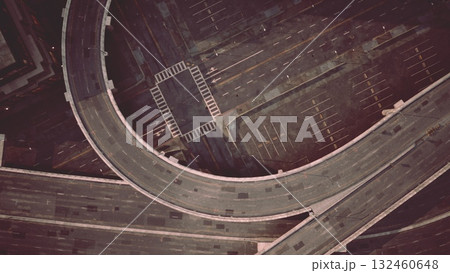 Empty streets create a surreal atmosphere as a winding road snakes through an urban landscape, showcasing the blend of modern architecture and shadows cast by streetlights at night. Empty streets create a surreal atmosphere as a winding road snakes through an urban landscape, showcasing the blend of modern architecture and shadows cast by streetlights at night. 132460648