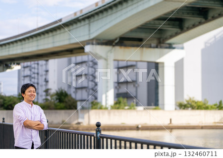 腕を組んで成功を確信する男性｜都市背景とコピースペース 132460711