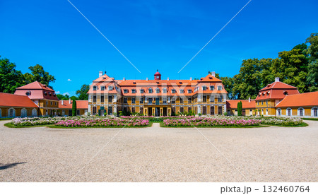 Panoramic view of Rajec Jestrebi Chateau on a sunny summer day with blue sky, blooming pink roses, and a fountain in front of the historical building. 132460764