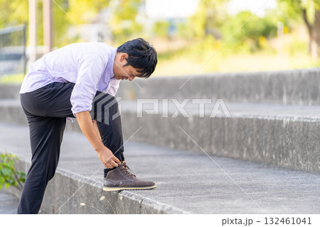 階段で靴紐を結ぶ男性 132461041