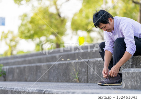 階段で靴紐を結ぶ男性 132461043