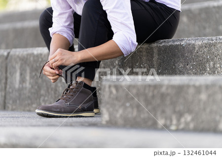 階段で靴紐を結ぶ男性 132461044