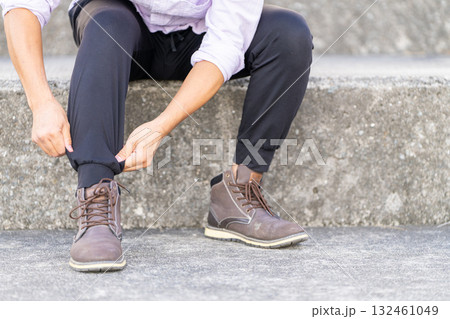 階段で靴紐を結ぶ男性 132461049