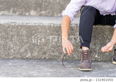 階段で靴紐を結ぶ男性 132461050