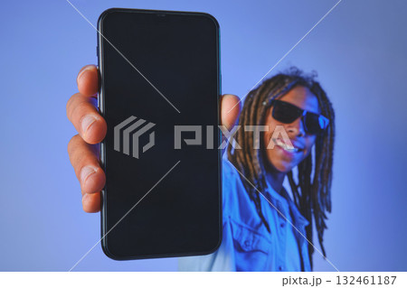 Young man wearing dreadlocks and sunglasses holding up a smartphone with an empty screen Young man wearing dreadlocks and sunglasses holding up a smartphone with an empty screen 132461187