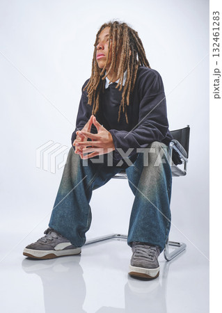 Young man with dreadlocks sitting pensive in studio 132461283