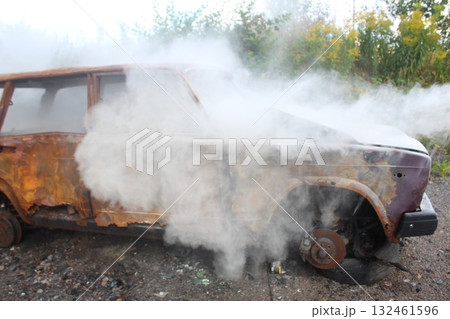 extinguishing the car with a fire extinguisher. The car is in white smoke. Fire 132461596