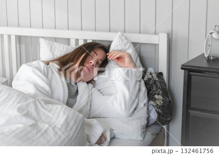A woman is sleeping peacefully in her bed with a white pillow and a blanket. A beautiful young happy lady is sleeping peacefully on a cozy bed in the morning light at home, in a relaxed atmosphere A woman is sleeping peacefully in her bed with a white pillow and a blanket. A beautiful young happy lady is sleeping peacefully on a cozy bed in the morning light at home, in a relaxed atmosphere 132461756