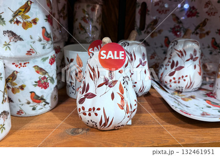 Painted ceramic gourds with autumn leaves and bird motifs displayed on a wooden shelf during a seasonal sale. Thanksgiving decor, ceramic home accents, fall clearance shopping, cozy interior trends 132461951