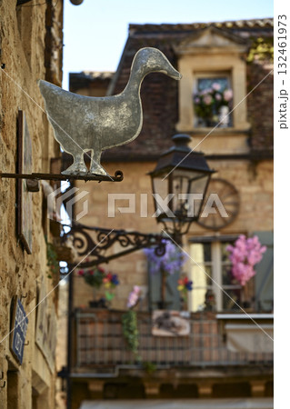 Charming streets of Sarlat-La-Caneda featuring a metal duck sign and beautifully decorated buildings 132461973